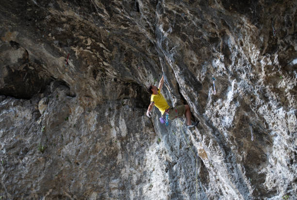 istock Man is climbing a very steep rock cave. 2161076320
