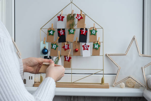 istock Number on craft paper notes with tasks before Christmas holidays. Female making kraft paper for handmade advent calendar Made with your own hands step by step DIY 2161077437