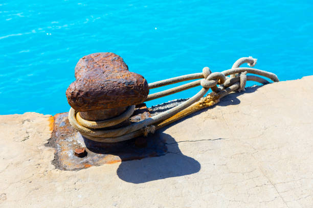 Rusty anchor is tied to a rope on a dock