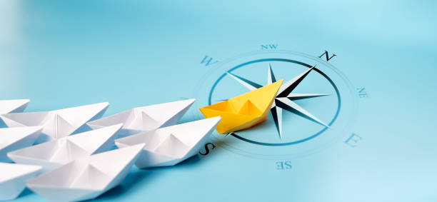 istock Yellow Paper Boat With Compass Leaving Mainstream And Changing Direction. 2161085449