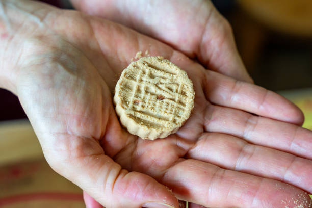 A hand is holding a round, brown cookie with Chinese characters on it.