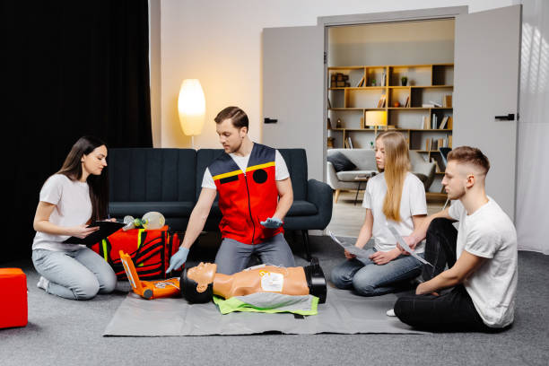 istock Young man instructor helping to make first aid heart compressions with dummy during the group training indoors 2161093674