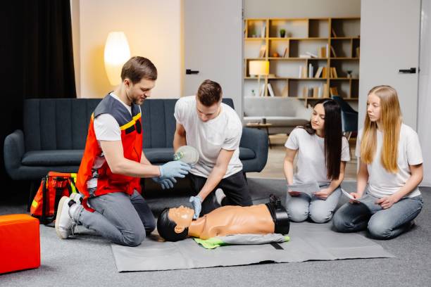 istock Young man instructor helping to make first aid heart compressions with dummy during the group training indoors 2161093684