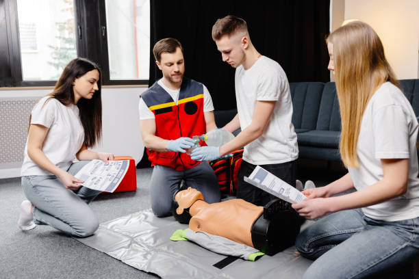 istock Young man instructor helping to make first aid heart compressions with dummy during the group training indoors 2161093690