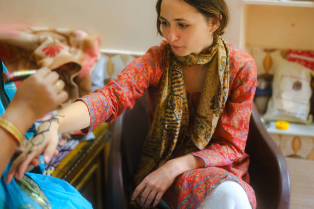 Woman getting henna  mehendi on her hand during experiential trip to India