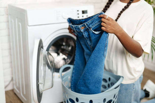 African Woman Loading Laundry Into Washing Machine in Home