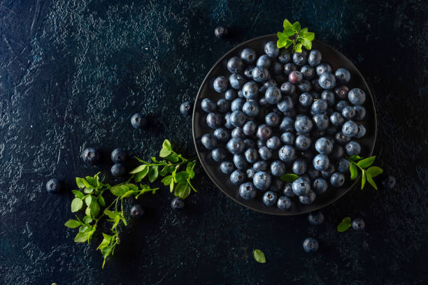 Blueberries in a black plate on a dark background.