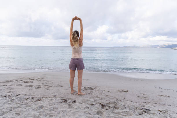istock Woman Stretching Towards the Sky on Beach 2161109207