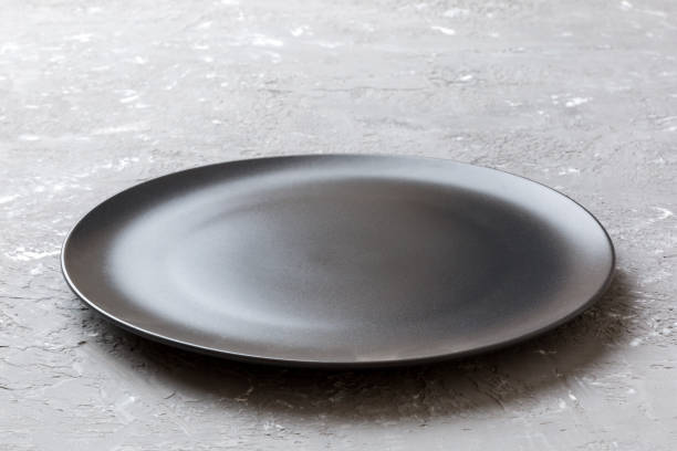 istock Perspective view of empty black plate on cement background. Empty space for your design 2161110142
