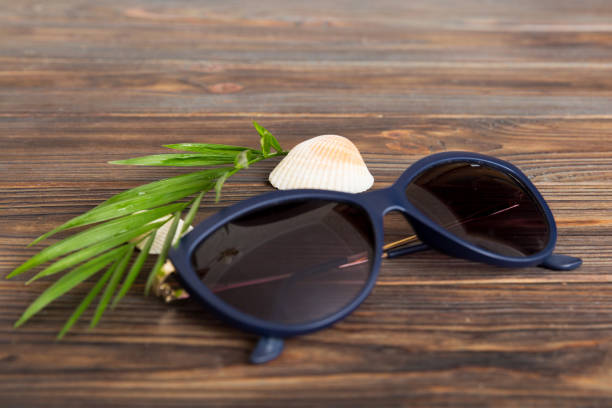 sunglasses with seashell lying on table background. Sunglasses on summer background. Top view flat lay with copy space for text.