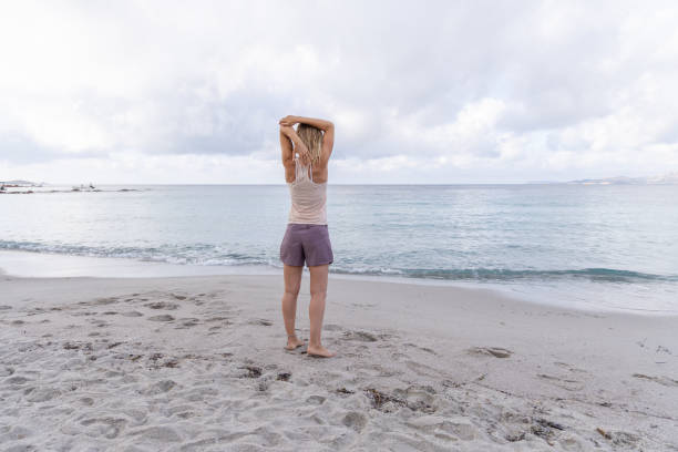 istock Woman Stretching on Tranquil Beach 2161110506