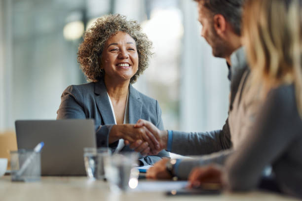 happy insurance agent shaking hands with her customers in the office. - försäkringsagent bildbanksfoton och bilder
