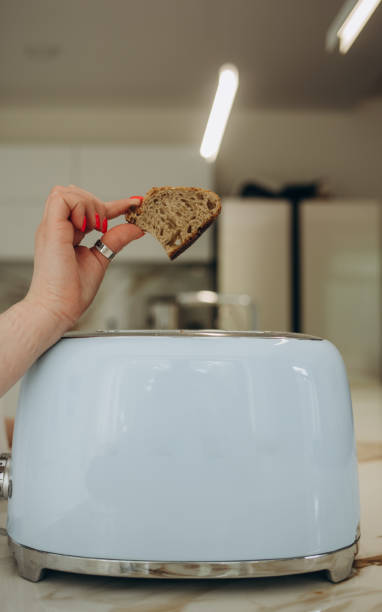 istock Young woman using toaster at table in kitchen 2161113722