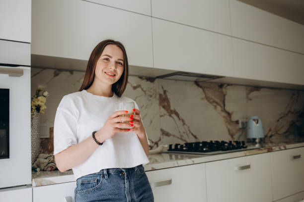istock Beautiful young woman drinking coffee in kitchen 2161114318
