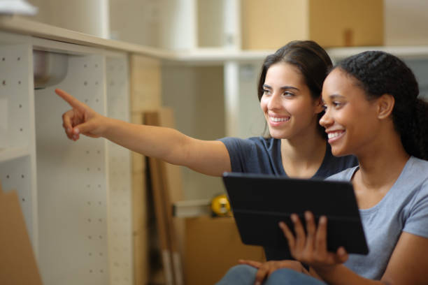 istock Two happy roommates checking online manual installing furniture 2161117549