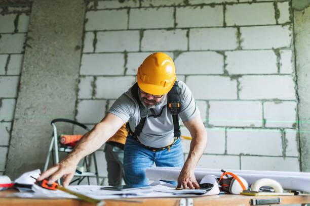 istock Mature adult construction worker working on blueprints at construction site 2161120910