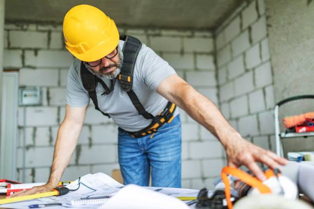 istock Mature adult construction worker working on blueprints at construction site 2161120917