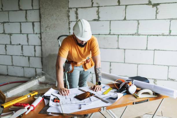 istock Mid adult construction worker reading blueprints at construction site 2161120920