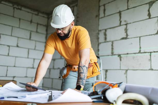 istock Mid adult construction worker reading blueprints at construction site 2161120970
