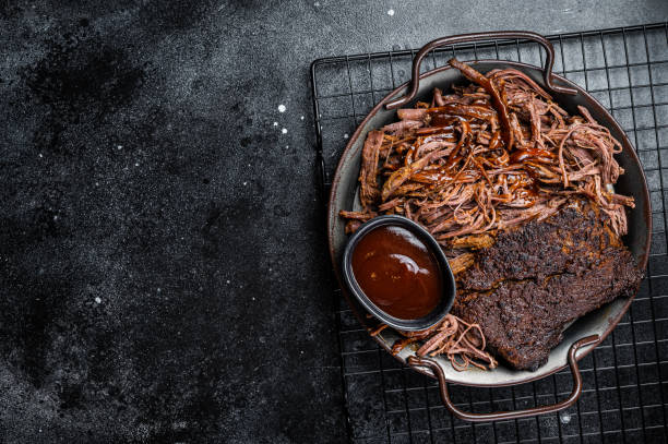 istock Slow Cooked Pulled Beef, Traditional meat rubbed with spices and smoked in a Texas smoker. Black background. Top view. Copy space 2161126339