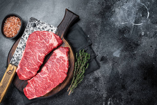 istock Marbled beef Denver raw meat steak with herbs. Black background. Top view. Copy space 2161128645