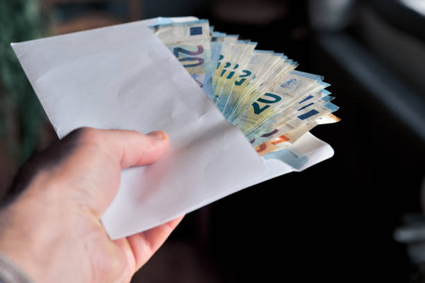 istock Man hand giving an envelope full of euros banknotes. 2161130414