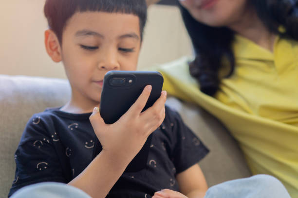 istock Close up cute little Asian boy with mom using smartphone, looking at screen 2161134682
