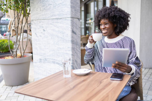 istock Woman drinking coffee at outdoor cafe while using tablet 2161135815