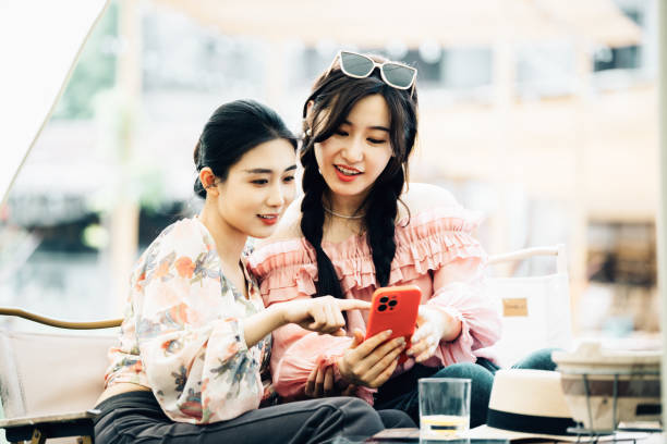 istock Two Asian girls sharing a funny moment while using smartphone together on their camp 2161136557