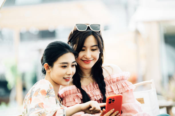 istock Two Asian girls sharing a funny moment while using smartphone together on their camp 2161136560