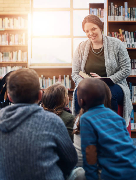 istock Library, children and teacher reading book, education and learning with knowledge, storytelling and kindergarten. Educator, woman and kids on floor, fun and fantasy stories with development or relax 2161136582