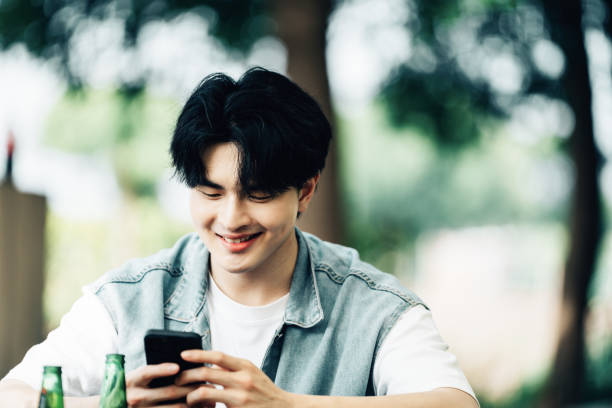istock Young Asian man with smatphone at party outside 2161136723
