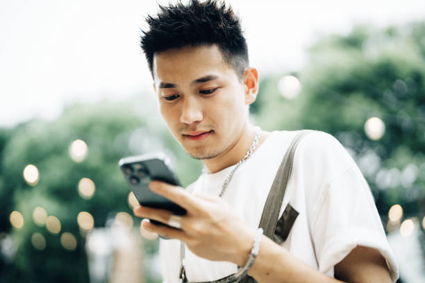 istock Young Asian man with smatphone at party outside 2161136873
