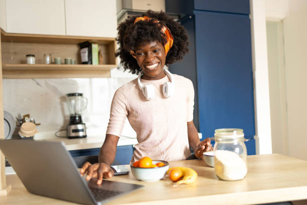 istock Woman using laptop in kitchen with healthy breakfast items 2161137224