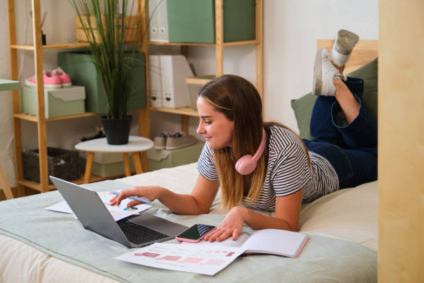 istock Young designer working from home lying on bed using laptop 2161141350