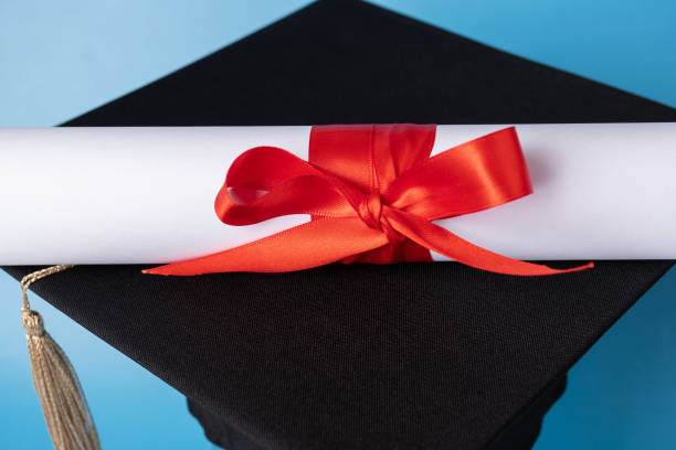 istock Graduation cap and diploma on blue background, graduating student with degree, university ceremony celebration 2161143229