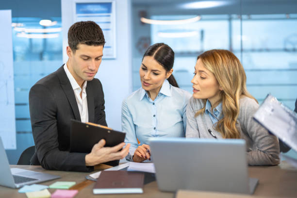 istock Business people in smart casual wear discussing documents and using a laptop while co-working in the office. 2161148411