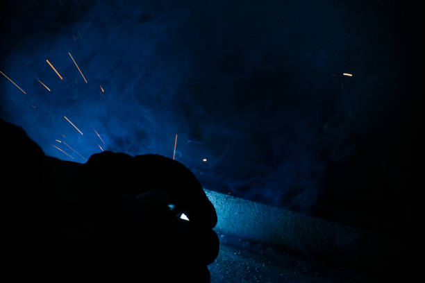 Skilled industrial welder with welding torch, working at his metal workshop