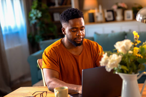 istock Young African American man sitting at home working while using laptop. 2161151955
