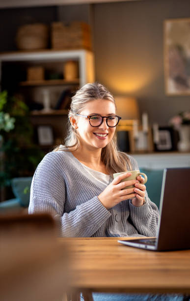 istock Smiling young woman working at home using laptop while sitting in her living room. 2161151992