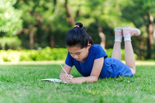 istock Little Girl Writing on Lawn 2161154412