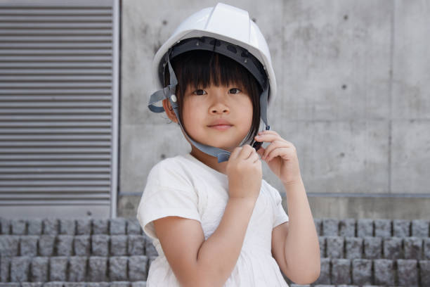 istock An elementary school girl wearing a helmet against a concrete building background. Evacuated to higher ground to save her life. 2161159059