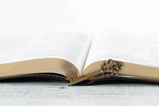 Ancient key and open holy bible book on wood with white background. Close-up. Copy space. Prophecy, revelation, blessing, answered prayer, wisdom, Christian biblical concept.
