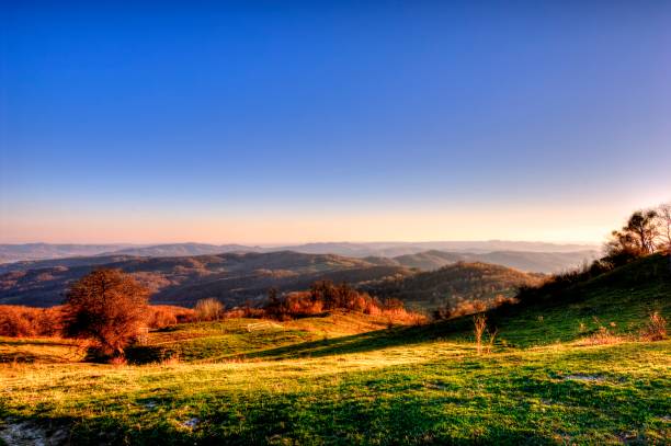 Stunning panorama of rolling mountains captured during the golden hour. The warm hues of the sunset light up the landscape, showcasing the natural beauty and tranquility. Ideal for nature, travel, and outdoor themes.