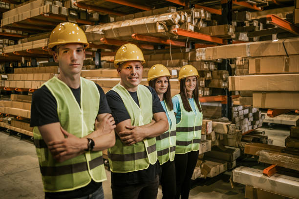 istock Warehouse workers in safety vests stand together in front of storage racks 2161188132
