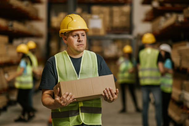 istock Warehouse worker carries box through busy distribution center 2161188617