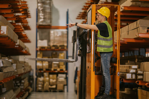 istock Warehouse worker operating forklift near shelving units 2161188675