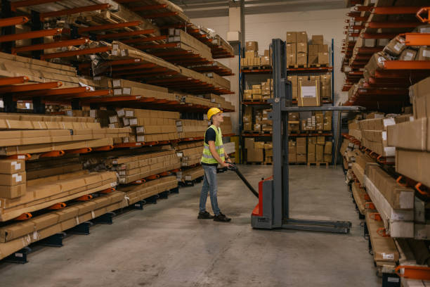 istock Warehouse worker operating pallet jack among cardboard boxes 2161188706