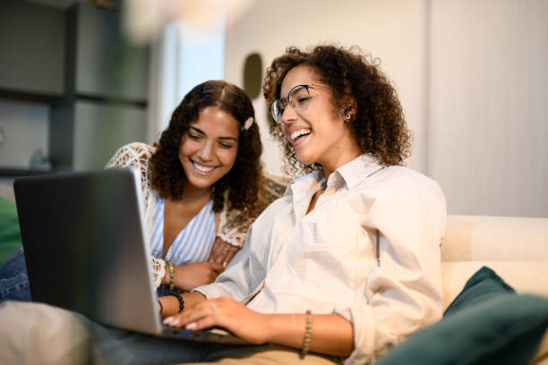 istock Sisters relaxing on the sofa with laptop 2161189116