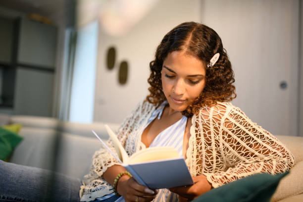 istock Woman reading book on sofa 2161189155